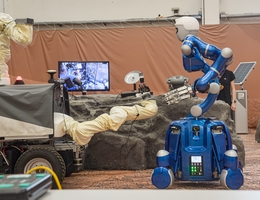 Die Surface-Avatar-Experimente sollen zeigen, wie unterschiedliche Roboter zusammenarbeiten. Hier geht DLR-Roboter Rollin‘ Justin auf den Interact Rover zu, der für das Szenario „gestrandet“ ist. Der humanoide Roboter soll die Gesteinsprobe des Rovers holen und für ihn zum Lander bringen. (Bild: DLR (CC BY-NC-ND 3.0))