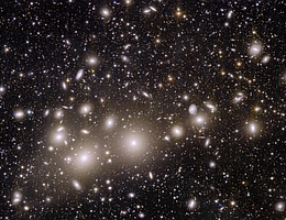 Galaxien des Perseushaufens sind in der Mitte des Bildes sichtbar und erscheinen als große Galaxien mit Halos um sie herum in Gelb und Weiß. Der Hintergrund dieses Bildes ist mit hunderttausend weiter entfernten Galaxien gefüllt, deren Farbe von weiß über gelb bis rot (für die am weitesten entfernten Objekte) reicht. Dieses Bild verdeutlicht Euclids Leistungsfähigkeit bei der Aufnahme extrem scharfer Bilder über einen großen Bereich des Himmels in einer einzigen Aufnahme. Dieses Farbbild wurde durch die Kombination der Daten der Instrumente Nahinfrarot-Spektrometer und Photometer (NISP) und Visible Instrument (VIS) gewonnen. (Bild: ESA/Euclid/Euclid Consortium/NASA, image processing by J.-C. Cuillandre, G. Anselmi; CC BY-SA 3.0 IGO)