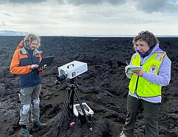 Feldkampagne im vulkanischen Island zur Vorbereitung für die Venus-Mission VERITAS Das Zentrum Islands ist eine einzigartige Vulkanlandschaft fast ohne Vegetation und ähnelt damit den Planetenoberflächen von Mond, Mars oder Venus. Deshalb wurde sie zum Ziel einer gemeinsamen Exkursion des Jet Propulsion Laboratory der NASA, des DLR und internationaler Wissenschaftlerinnen und Wissenschaftler. In Vorbereitung auf die bevorstehende NASA-Mission VERITAS zur Venus misst die Expedition die physikalischen und morphologischen Eigenschaften verschiedener Arten von Vulkanlandschaften. Dr. Solmaz Adeli (rechts) und Dr. Stephen Garland (links) vom DLR-Institut für Planetenforschung untersuchen den jungen Lavastrom Holuhraun, der erst 2014 entstanden ist, mit der Infrarotkamera V-EMulator, einem Prototyp für den VEM (Venus Emissivity Mapper), den das DLR für VERITAS entwickelt. (Bild: DLR)