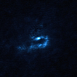 Dieses Bild des jungen Sterns V960 Mon und des staubhaltigen Materials in seiner Umgebung wurde mit dem Atacama Large Millimeter/submillimeter Array (ALMA) aufgenommen, an dem die ESO beteiligt ist. Große Staubklumpen mit planetenähnlichen Massen sind hier als blaue Flecken sichtbar. Diese Klumpen könnten sich zusammenziehen und durch einen Prozess, der als „Gravitationsinstabilität“ bekannt ist, in sich zusammenfallen und Riesenplaneten von der Größe des Jupiters bilden. (Bild: ALMA (ESO/NAOJ/NRAO)/Weber et al.)