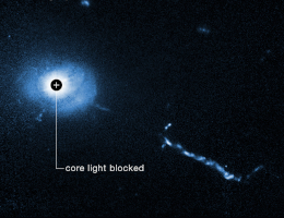 Ein Bild des Hubble-Weltraumteleskops vom Kern des Quasars 3C 273. Ein Koronagraph auf Hubble blockiert die Blendung, die von dem supermassiven schwarzen Loch im Herzen des Quasars ausgeht. Dadurch können die Astronomen noch nie dagewesene Details in der Nähe des Schwarzen Lochs erkennen, wie z. B. seltsame Filamente, Lappen und eine mysteriöse L-förmige Struktur, die wahrscheinlich von kleinen Galaxien verursacht wird, die von dem Schwarzen Loch verschlungen werden. Der 2,5 Milliarden Lichtjahre entfernte 3C 273 ist der erste Quasar (quasi-stellares Objekt), der 1963 entdeckt wurde. (Bild: NASA, ESA, Bin Ren (Université Côte d'Azur/CNRS); Danksagung: John Bahcall (IAS); Bildverarbeitung: Joseph DePasquale (STScI))